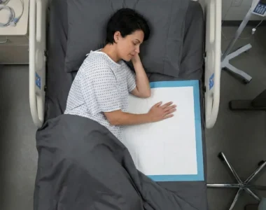 Hospital patient sleeping on side with disposable bed pad in medical room, top view of inpatient care setting